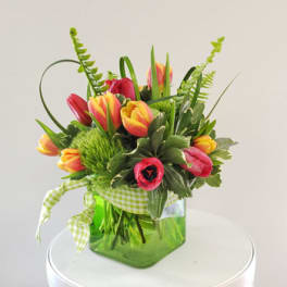 Tulip bouquet in a green glass vase with a gingham ribbon