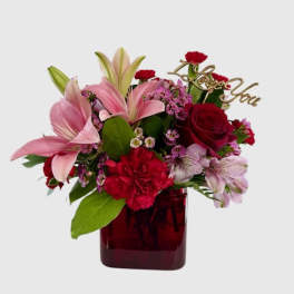 Bouquet of pink lilies, red roses, and carnations in a red vase