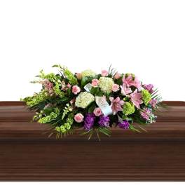 Pink and white floral casket spray on a wooden casket