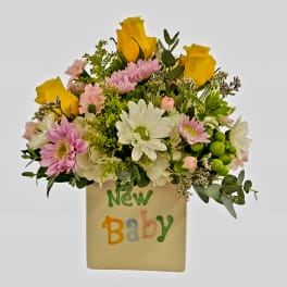 Bouquet of yellow roses and pink daisies in a vase labeled New Baby
