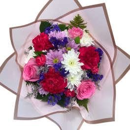 Mixed bouquet of pink, white, red, and purple flowers wrapped in pale paper