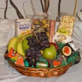 Gift basket with fruit, snacks, and candy in a wicker tray