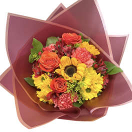 Bouquet of yellow daisies, orange roses, and pink carnations wrapped in burgundy paper