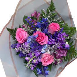 Bouquet of pink roses and purple flowers wrapped in translucent paper