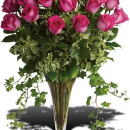 Pink roses in a tall glass vase with trailing ivy