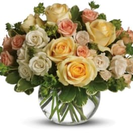 Bouquet of cream, peach, and yellow roses in a clear glass vase