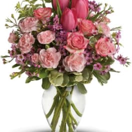 Pink tulips and roses arranged in a clear glass vase