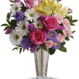 Mixed bouquet of pink roses, daisies, and lilies in a silver vase