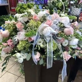 Large pastel floral arrangement with pink and white blooms and ribbon
