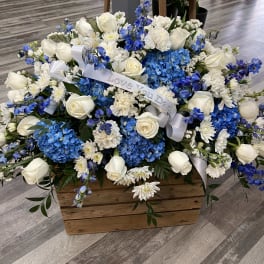 Blue and white floral arrangement in a wooden box with a ribbon
