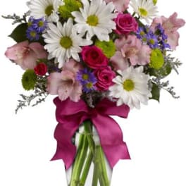 Mixed bouquet of daisies, roses, and pink lilies in a glass vase