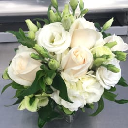 White roses and pale green lisianthus in a clear glass vase