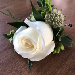 White rose boutonniere with green foliage and small filler flowers