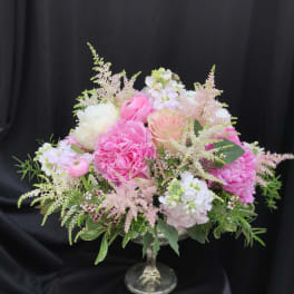 Pink and white floral arrangement in a glass pedestal vase