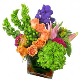 Colorful bouquet with orange roses, purple orchids, and green hydrangeas in a glass vase