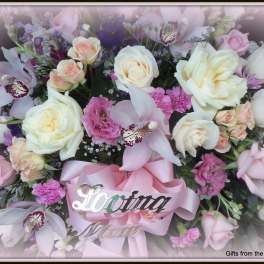 Pink and white floral arrangement with a pink ribbon and "Loving Mom" sign