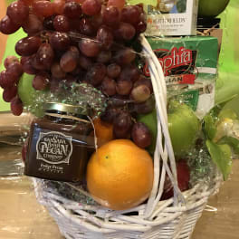 Gift basket with grapes, oranges, candy, and a white wicker basket