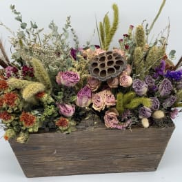 Dried flower arrangement in a wooden box with purple and peach blooms