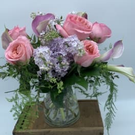 Pink roses and lavender flowers arranged in a glass vase