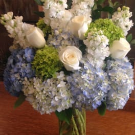 Vase arrangement of white roses, white stock, and green and blue hydrangeas