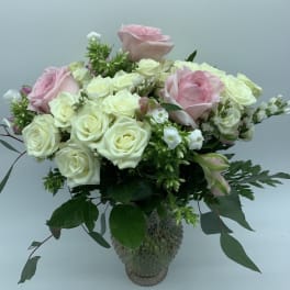Pink and white roses arranged in a glass vase