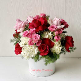 Pink and red roses arranged in a white container