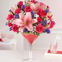 Pink lilies and roses arranged in a martini glass vase