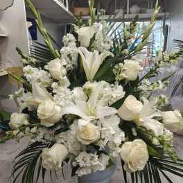 Large white floral arrangement in a gray vase with roses and lilies