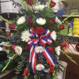 Large red, white, and blue floral standing spray with roses and ribbon