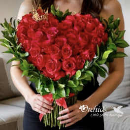 Heart-shaped bouquet of red roses with green foliage and a red ribbon