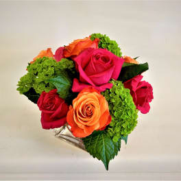Bouquet of pink, orange, and red roses with green hydrangeas