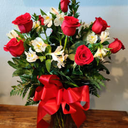 Bouquet of red roses and white alstroemeria in a glass vase with a red ribbon
