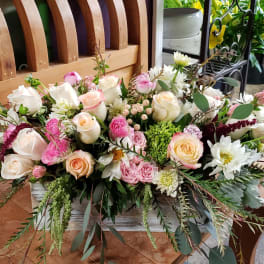 Low centerpiece of pink and cream roses with mixed blooms in a white wooden box