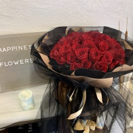Large bouquet of red roses wrapped in black and beige tulle