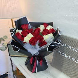Bouquet of red and white roses wrapped in black paper