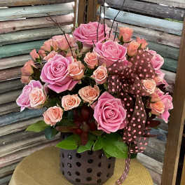 Pink and peach roses arranged in a polka-dot vase with a ribbon
