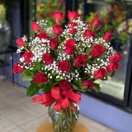 Bouquet of red roses and baby's breath in a glass vase with a red ribbon
