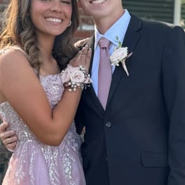 Couple in formal attire wearing matching blush rose wrist corsage and boutonniere