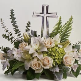 White floral arrangement with roses and lilies beneath a clear cross