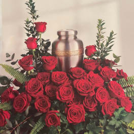 Red roses arranged around a silver urn with greenery