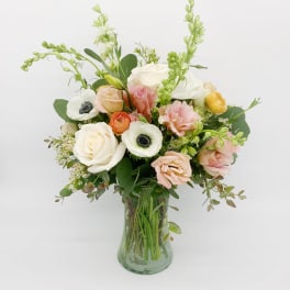 Pastel bouquet of mixed flowers arranged in a clear glass vase.