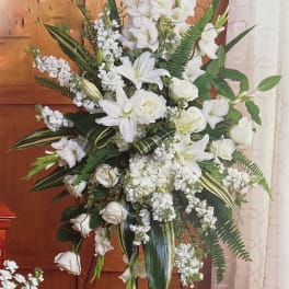 Tall white floral spray on a stand with lilies and roses