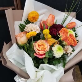 Bouquet of orange and peach roses with mixed chrysanthemums wrapped in white and taupe paper