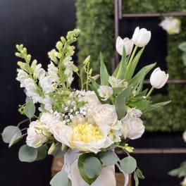 White and pale blush floral arrangement in a round white box