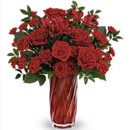 Red roses and carnations in a tall red glass vase