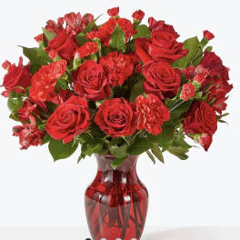 Red roses and carnations in a red glass vase