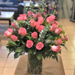 Large arrangement of pink roses in a clear glass cylinder vase.