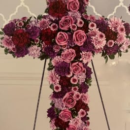 Large floral cross on an easel with pink and purple flowers
