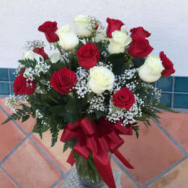 Bouquet of red and white roses in a glass vase with a red ribbon