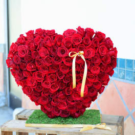 Heart-shaped arrangement of red roses with a yellow ribbon